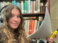 woman holding paper and highlighter in front of bookshelf, photo taken by Frankie Boyko